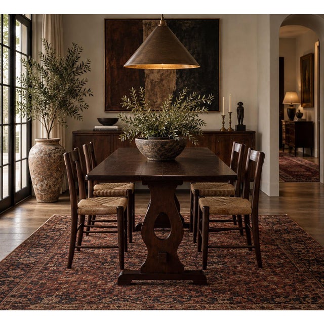 This antique wooden dining table features a sculptural trestle base with pierced pedestal supports, exposed joinery...