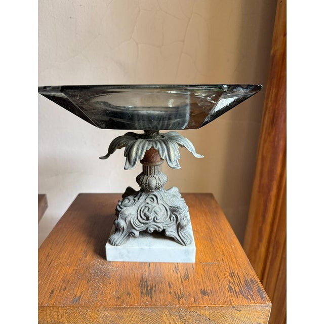 Mid-century Hollywood Regency pedestal centerpiece bowl featuring a thick smoky-gray molded glass dish set on an ornate...