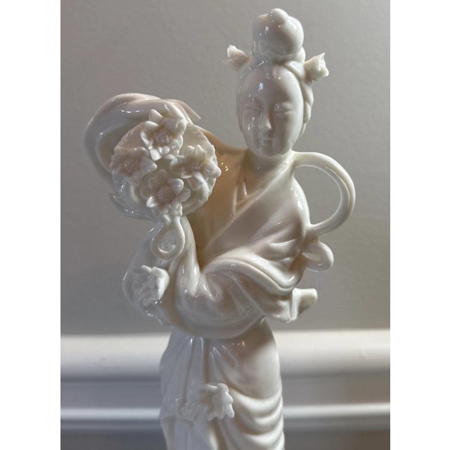 An antique Chinese blanc de Chine porcelain figure of Guanyin, circa 1930. The white porcelain figure stands with raised...