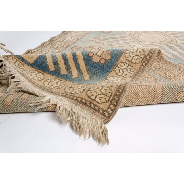 This is a vintage Turkish Oushak rug from the Mid 20th Century. The piece was hand-knotted.