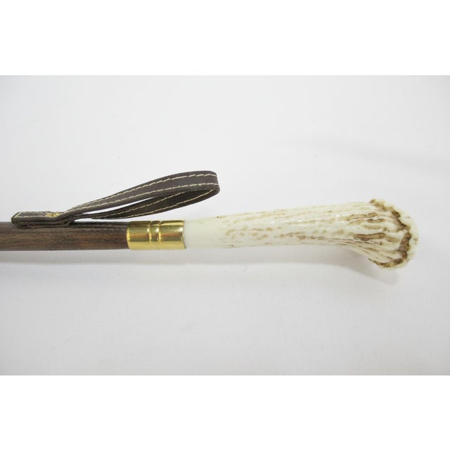 Vintage shoe horn featuring a natural Ox horn tongue and stag antler handle. Wooden shaft with a brass sleeves. Measures...