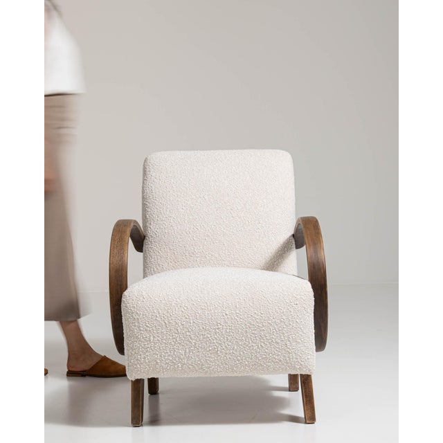 This mid 20th century armchair from Czech Republic is finished in ivory, worked in wood. Its upholstered detailing gives...
