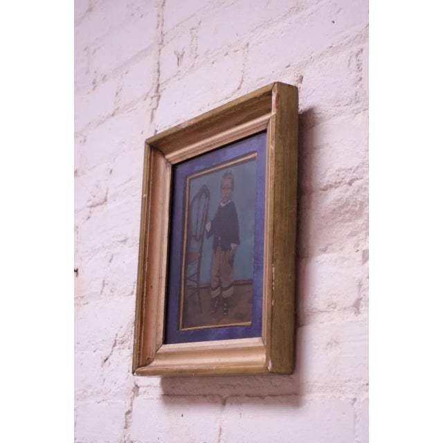 Circa 1930s tintype of a small boy holding onto a chair for support. Includes period-frame in giltwood with wear...