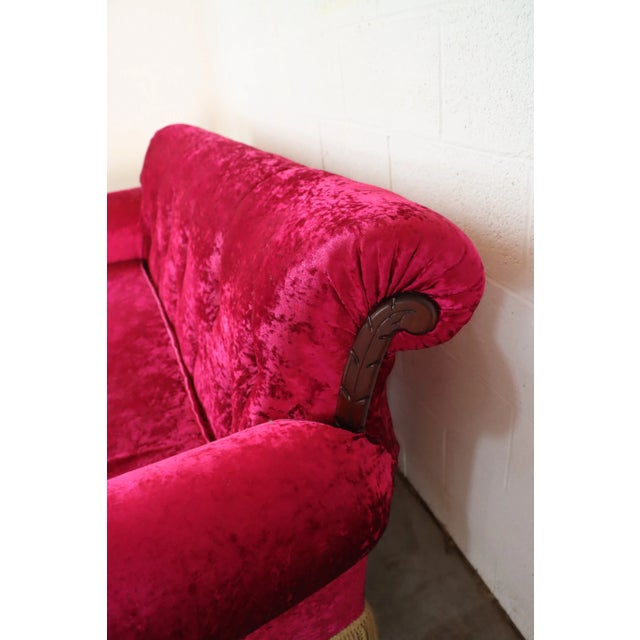Hollywood regecny style fuchsia sofa with tufted back, tassel trim ad rolled arm in crushed velvet.