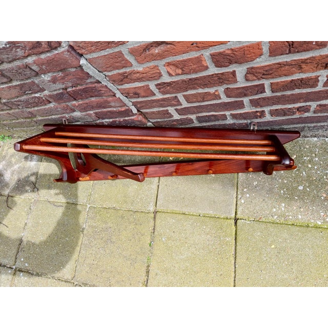 Beautifully designed, asymmetrical teak coat rack with oak hooks. It features standard hooks, a folding arm, and a hat...