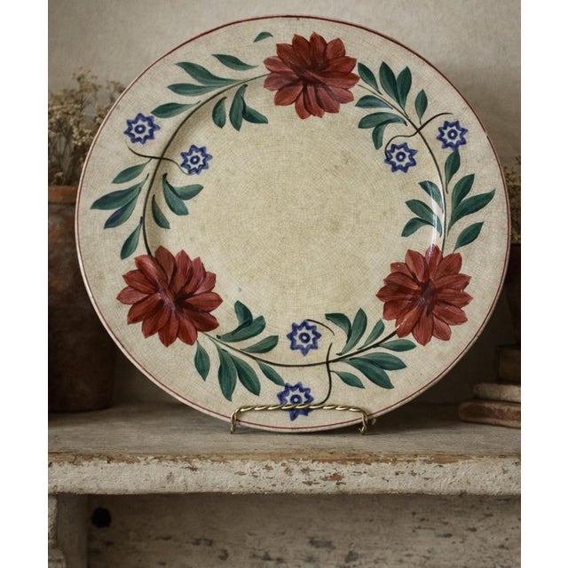 A charming antique European earthenware charger dating to the late 19th or early 20th century. Hand-painted with bold red...