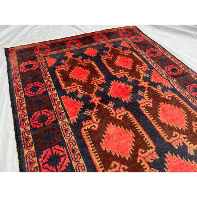This stunning vintage Afghan hand-knotted runner rug features a bold geometric pattern in warm terracotta, deep brown, and...