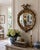 A Federal-style giltwood convex mirror crowned with a carved eagle, its wings outstretched above a laurel motif—an...