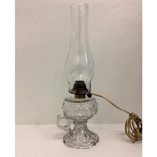 Precious antique electrified oil lamp from the early 20th century. The pressed glass lamp has an egg pattern and holds a...