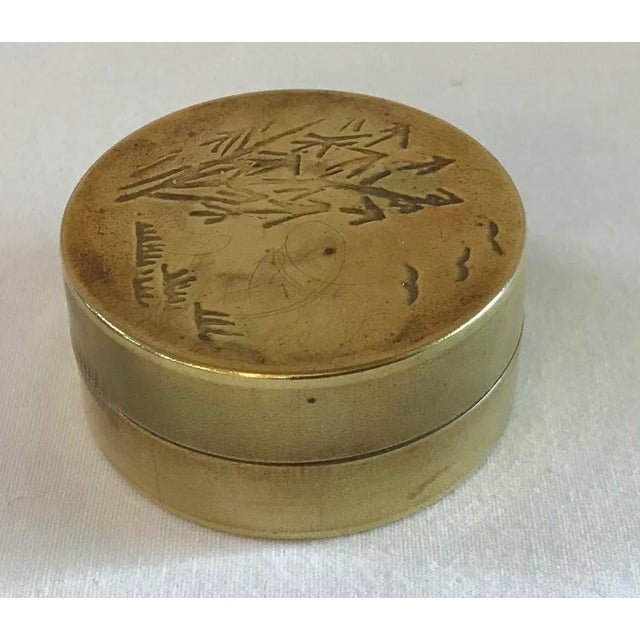Round brass trinket box with an asian etched design.
