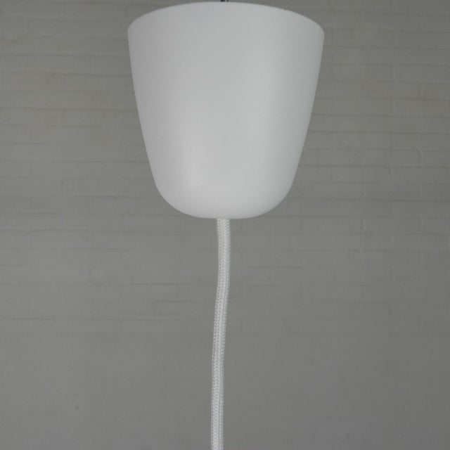 Ufo-shaped pendant lamp with white glass on top and clear glass with white stripes below. the edges are provided with gold...