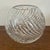 A vintage cut crystal fish bowl or vase featuring a heavy swirl cut design and rounded form. Measures approx: 7W x 7D x...