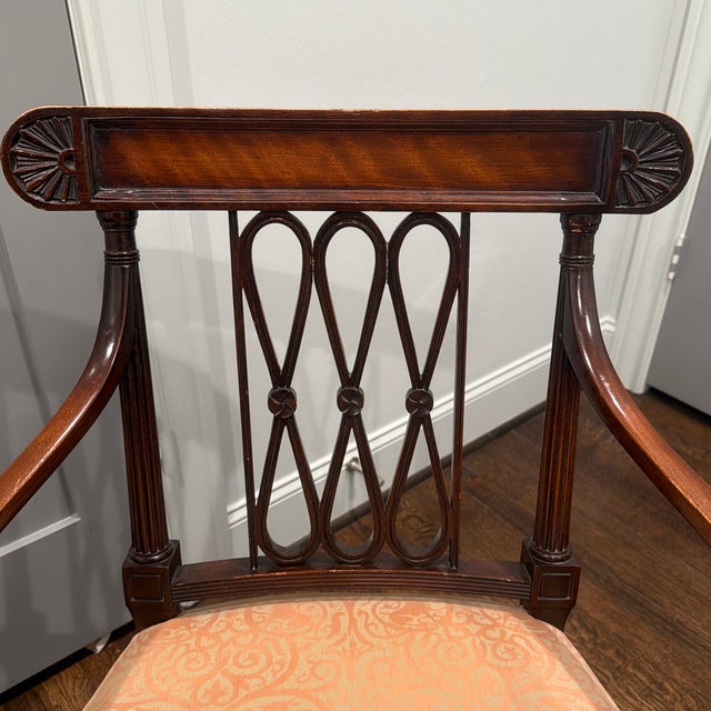 Classic neoclassical accent chair featuring a rich mahogany finish, carved fan motifs, fluted legs, and an elegant open-...