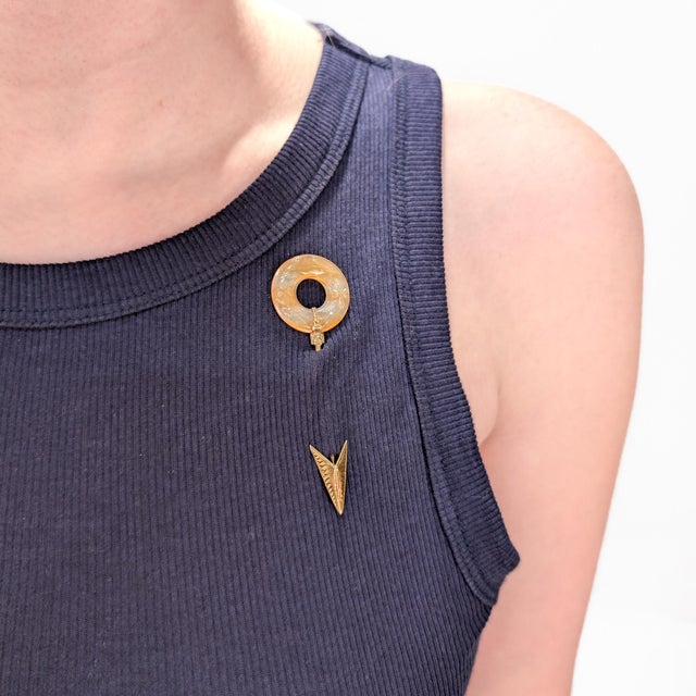 A fine antique Art Deco jabot pin. In 14 karat yellow gold. With a carved circular agate or quartz disc with orange and...