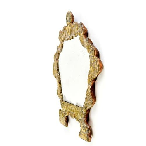A mirror with a wooden frame covered in finely chiseled brass.