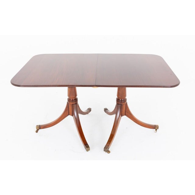 This elegant mahogany dining table is crafted in the Regency Revival style and stands on two substantial pedestal bases...