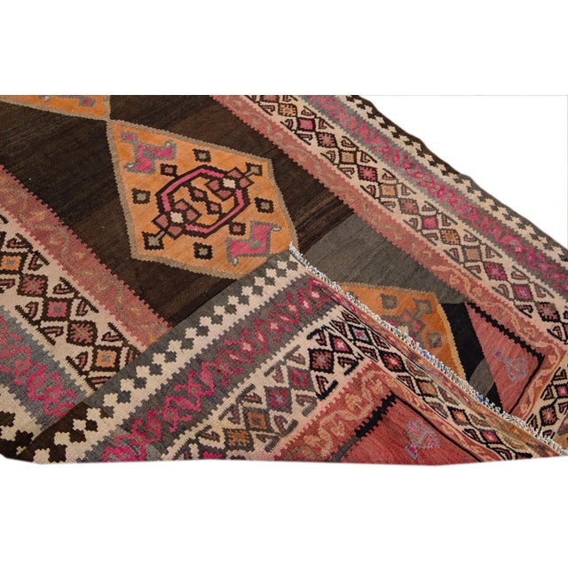 Beautiful kilim handmade wool runner with a brown field. This Vintage flatweave rug has orange, gray, and beige accents...