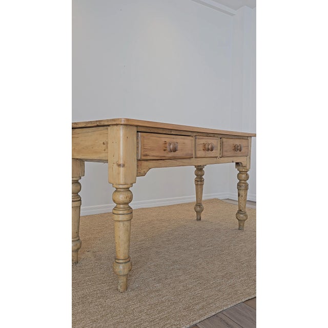 Dimensions: 55.5"W x 22"D x 30.25"H Floor to skirt: 21.75"H A charming antique pine table with beautifully turned legs and...