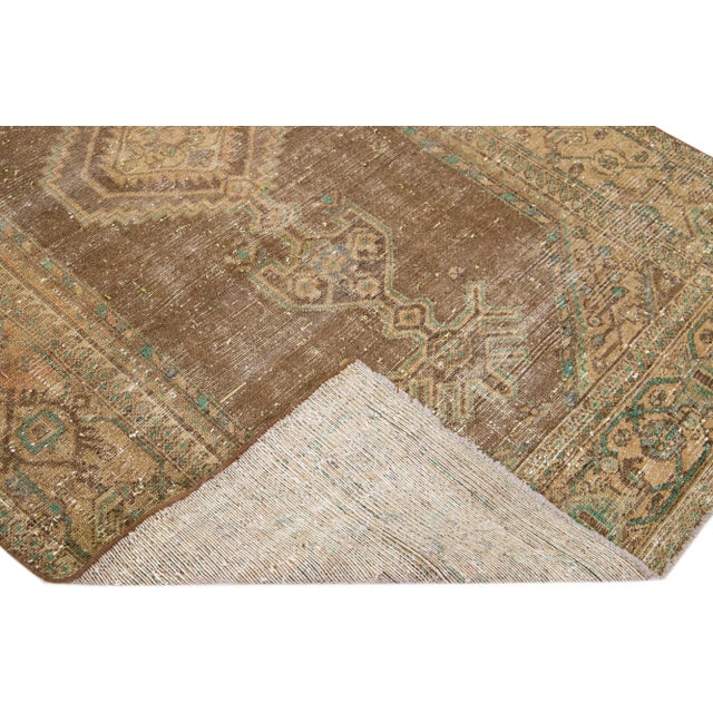 Beautiful vintage Persian distressed hand-knotted wool rug with a brown color field. This piece has multicolor accents in...