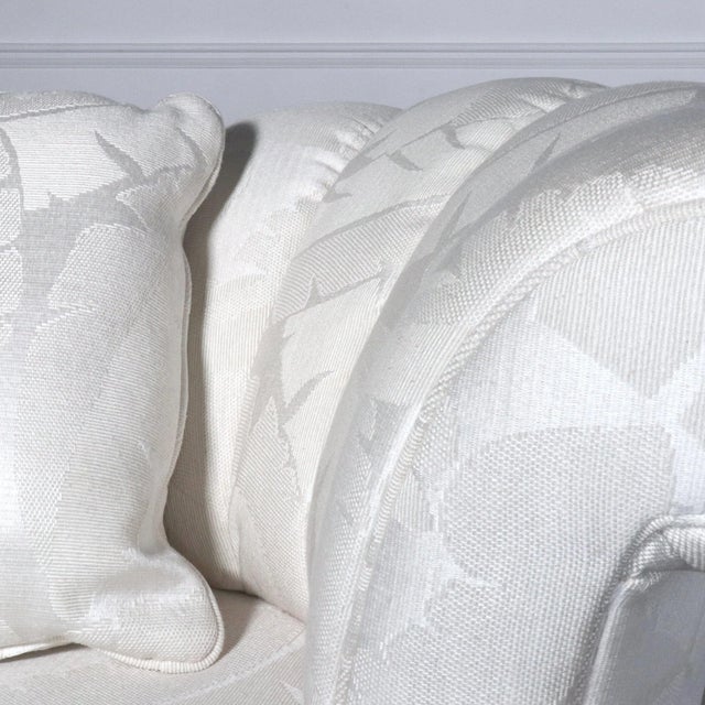 Channel back nautilus swivel lounge chair in a white palm leaf motif upholstery. Coordinating throw pillow. In the manner...