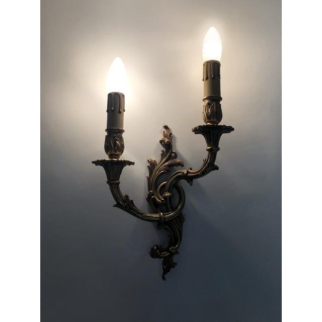 Antique pair of double-light bronze wall sconces with acanthus leaf motif. Large pair of bronze wall sconces, each topped...