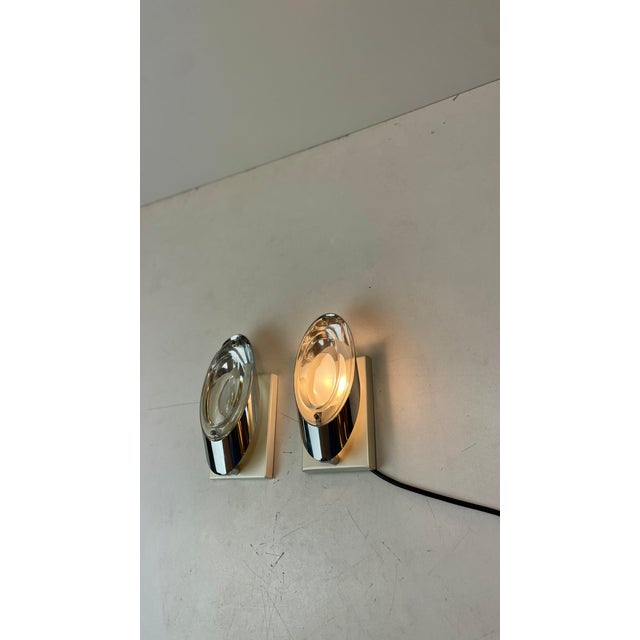 Set of two space-age sconces made with the iconic patented optical lenses in lead crystal, inlaid in a chrome-plated steel...