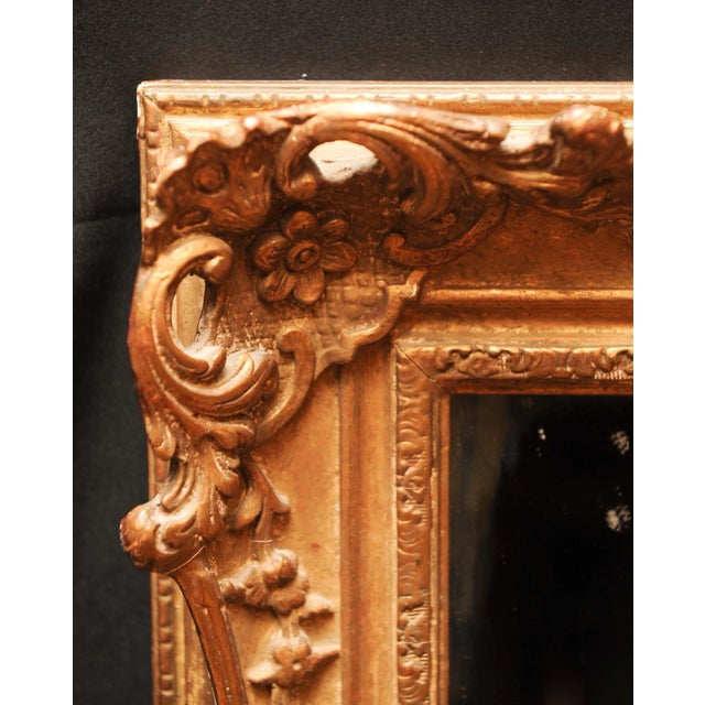 This wall mirror features flowers and scroll motifs.