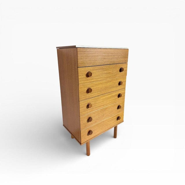 A beautifully proportioned mid-century teak chest of drawers, featuring a clever lift-up mirror compartment that adds both...