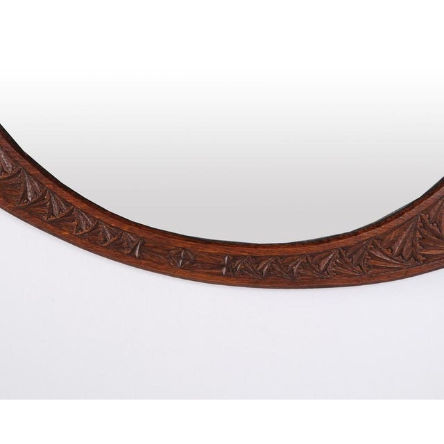 Oval mirror with a carved wooden frame. Dating from the 1890s, it features decorative details characteristic of the...