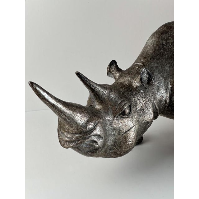 A large rhinoceros sculpture crafted around the late 1980s, in England, This sculptural piece of animalia, showcases a...