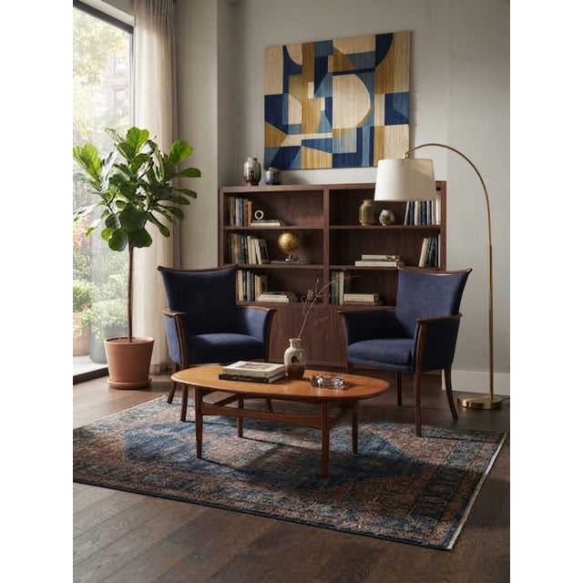 An exquisite and matching pair of fully refurbished vintage lounge armchairs, featuring rich dark-toned solid wooden...