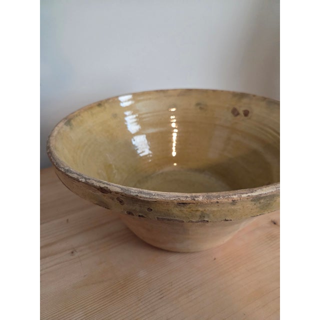 This French glazed terra cotta tian bowl in warm cream and honey tones is the kind of object that earns its place without...