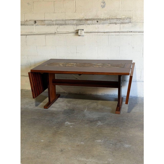 This striking extendable dining table features a robust trestle base and a functional drop-leaf design. The rectangular...