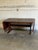 This striking extendable dining table features a robust trestle base and a functional drop-leaf design. The rectangular...
