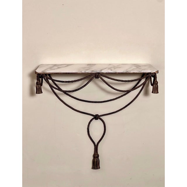 Italian gilt iron rope and tassel wall mount console with a white marble top, circa 1960s. An exquisite console of a full-...