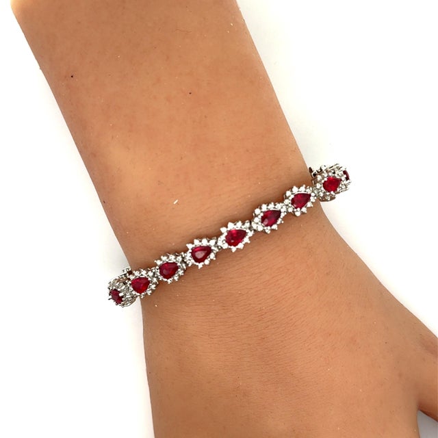 A contemporary tennis bracelet crafted in 14k white gold. The design features pear-cut rubies, totaling 9.10 carats,...