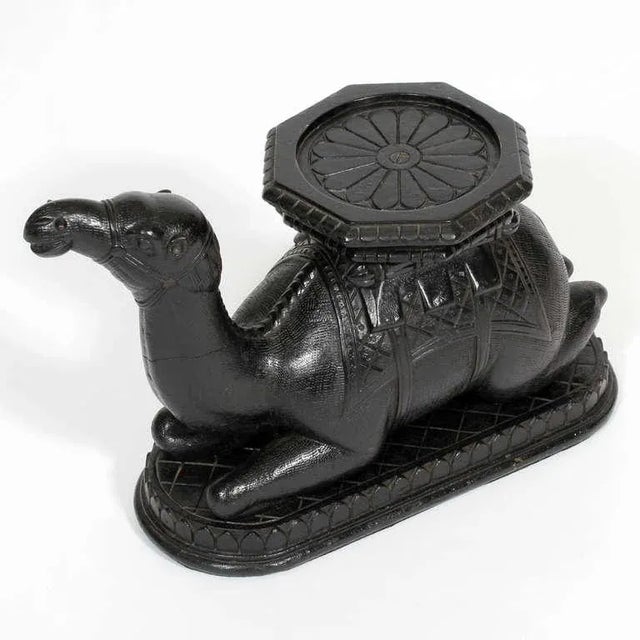 A rare size and form Anglo Indian carved and ebonized camel pedestal or vase holder. A camel in the lying position, with...