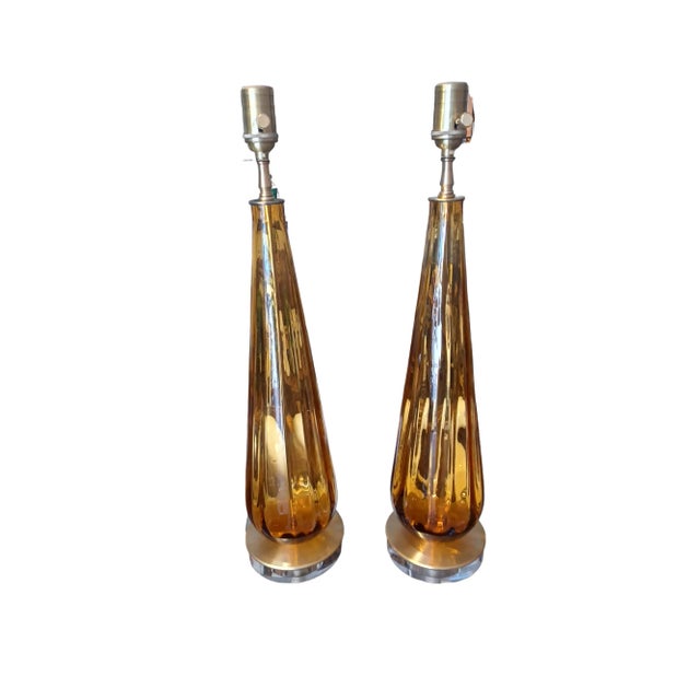 Vintage mid century pair of handblown glass table lamps. Lamps are an oblong teardrop shape and amber in color. They sit...
