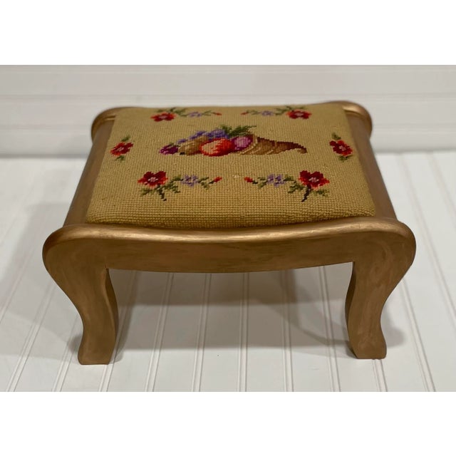 Victorian footstool with cornucopia needlepoint and antique gold finish on the wood frame. The needlepoint comprises of...