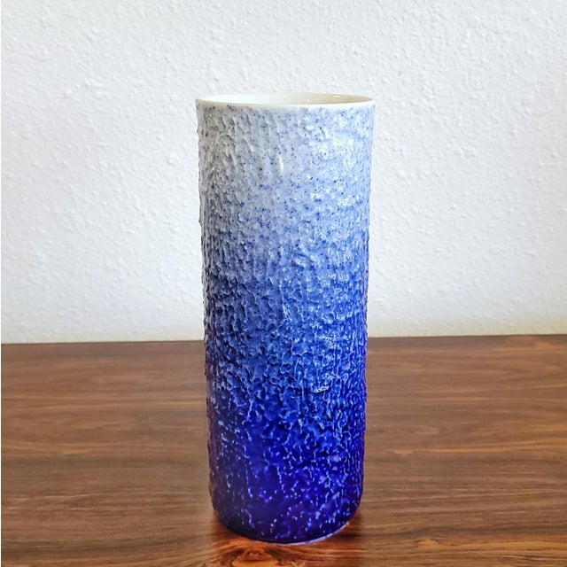 A beautiful HUTSCHENREUTHER color-gradient cylinder vase with a highly textured surface and a glossy finish of dark blue...