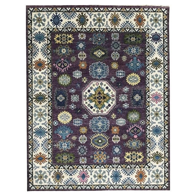 This hand knotted pile rug features a classic traditional style rendered in primary shades of purple, lavender, and mauve....