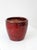 A vintage studio pottery planter with a rich oxblood glaze that shifts from deep red to near black at the rim. The softly...