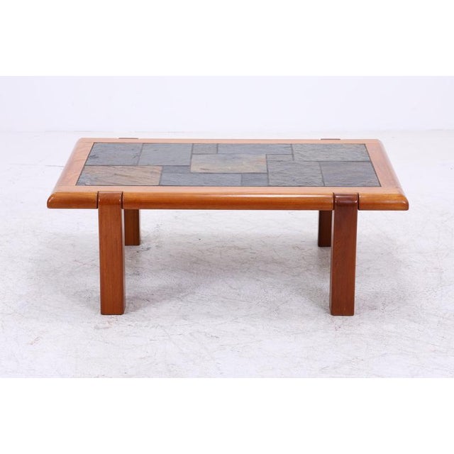 Vintage teak coffee table with an intricately inlaid slate top. The sturdy wooden frame, rounded edges, and the...
