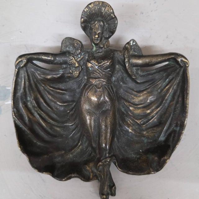 An elegant Art Nouveau figural vide-poche cast in a copper-based metal alloy, depicting a female dancer with outstretched...