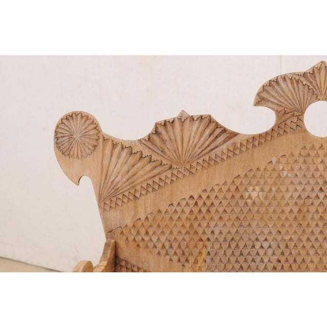 A Spanish carved wooden arm-bench with back from the mid 20th century. This vintage natural wood bench from Spain is adorn...