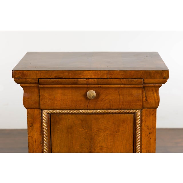 A pair of Italian walnut bedside cabinets from circa 1800 with single drawer and single door, carved giltwood twisted rope...