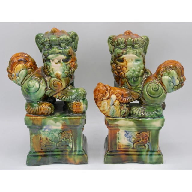 A stunning pair of mid 20th century Asian ceramic foo dogs in excellent bright colors and unique designs. This is a...