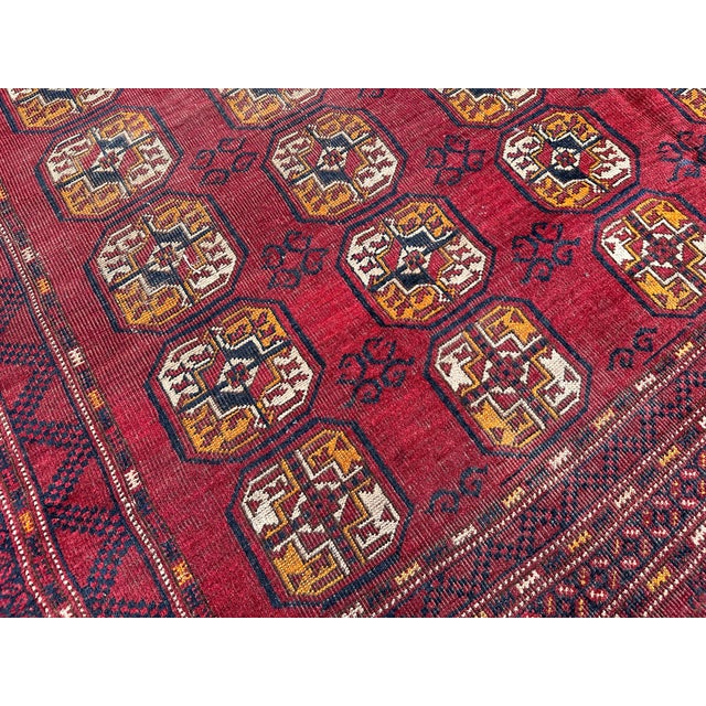 This hand-knotted Ersari Bokhara rug features dense rows of octagonal "elephant's foot" guls in gold, rust, and ivory set...