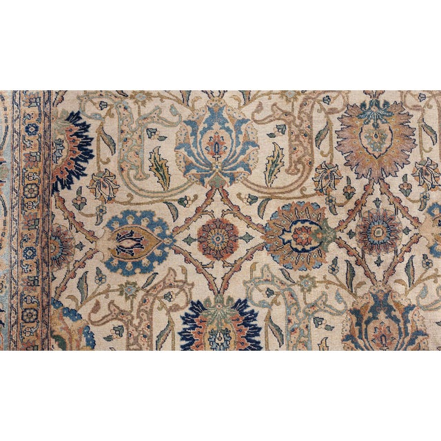 This antique Persian Tabriz rug, dating back to around 1920, features a sophisticated botanical design with an all-over...