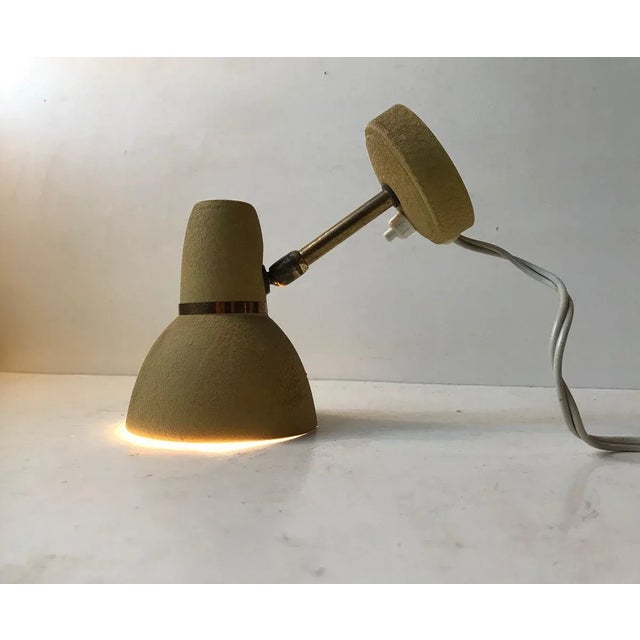 Adjustable Wall lamp made from brass and aluminium. The pastel mustard yellow lacquer has been applied in such a way that...